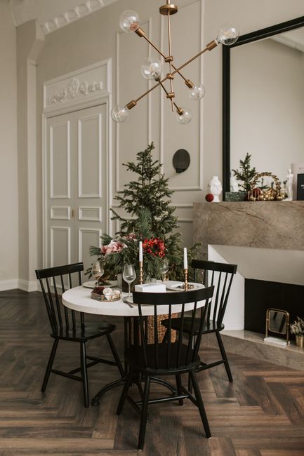 Stylish room with a Christmas tree, table, and modern chandelier, perfect for festive settings.