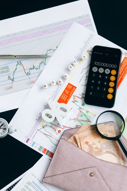 Flat lay of financial charts, smartphone calculator, and documents for market analysis.