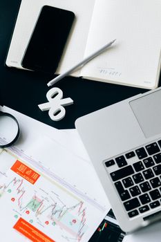 A stylish office setup featuring financial charts, laptop, and smartphone for data analysis.
