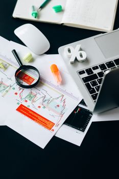 A top view of a workspace featuring financial documents, a laptop, and office supplies emphasizing data analysis.