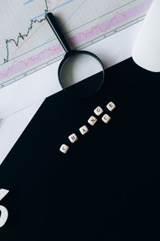 A conceptual still life showcasing a magnifying glass, financial chart, and wooden blocks spelling 'CHANGE'.