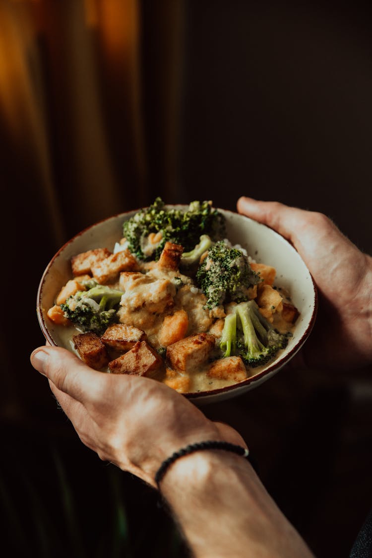 Person Holding A Bowl Of Cooked Tofu And Broccoli