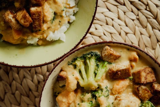 Tasty vegan bowl with broccoli, tofu, and creamy sauce served on a woven mat.