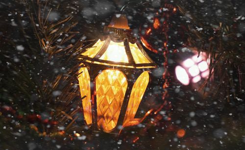 Free Close-up of an illuminated Christmas lantern surrounded by snowflakes, creating a festive winter mood. Stock Photo