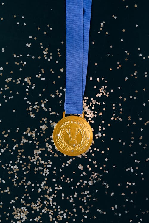 Close-Up Shot of a Gold Medal on a Black Surface