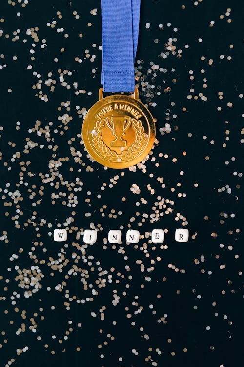 Close-Up Shot of a Gold Medal on a Black Surface