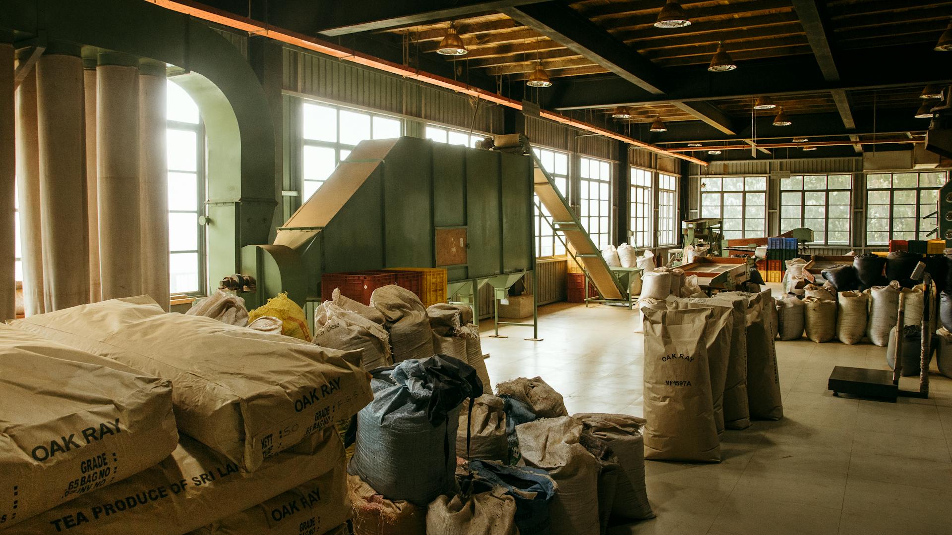 Inside a Sri Lankan tea factory with sacks and machinery creating a traditional processing scene.