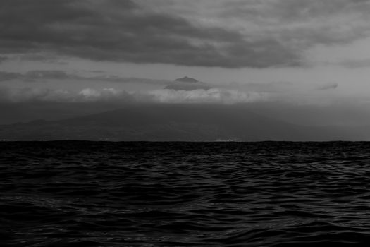 Grayscale Photo of the Sea and Mountain