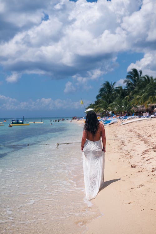 Free A Woman in a White Dress Walking on a Shore Stock Photo