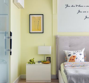 Comfortable bedroom with contemporary interior and bed decorated with soft pillow near wall with inscriptions