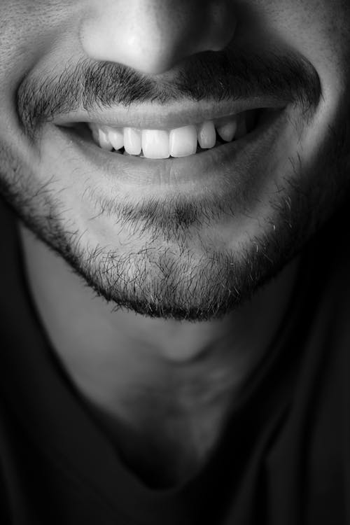 Black and white closeup of crop anonymous male with beard and mustache wearing casual t shirt