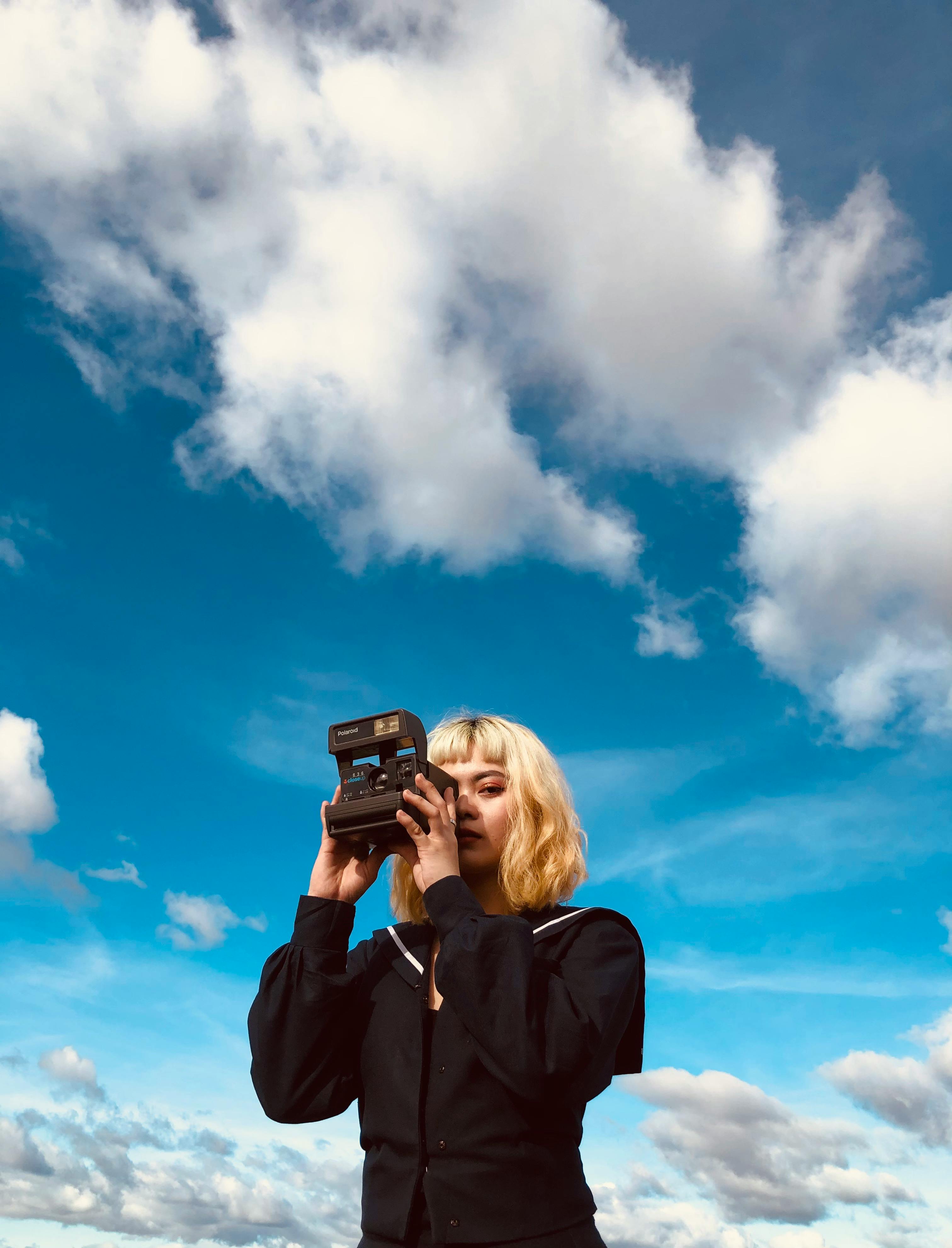 female with instant camera against blue sky