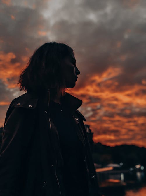 Woman in Black Jacket Standing during Sunset 