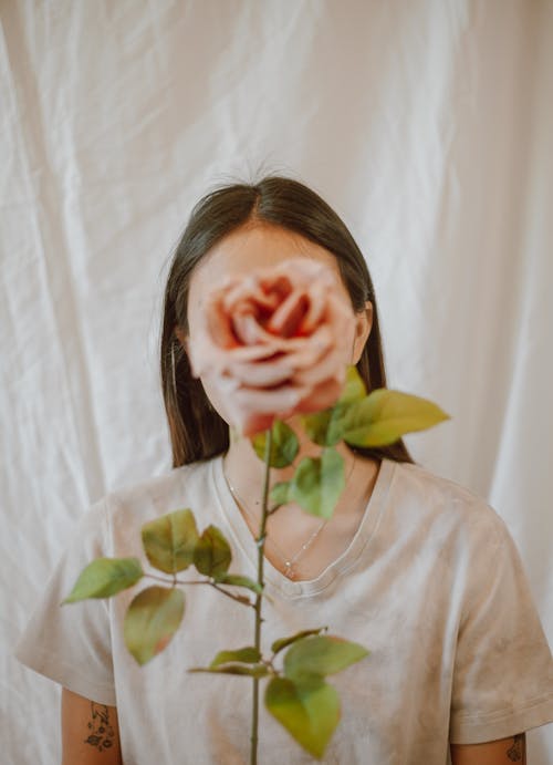 Woman with fresh rose against white drapery