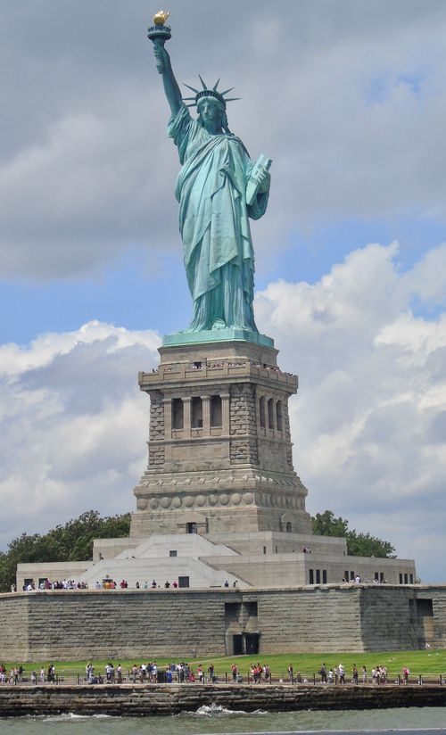 Free Statue of Liberty towering over Liberty Island with visitors, symbolizing freedom and democracy. Stock Photo