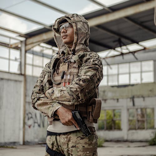 Serious ethnic warrior standing with gun in abandoned building