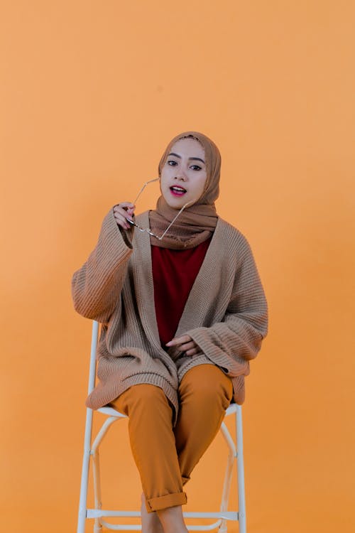 Stylish content Islamic woman putting on sunglasses in studio