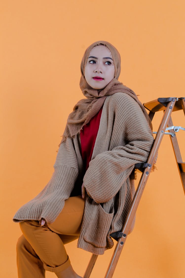 Young Islamic Woman In Hijab Sitting In Stepladder In Studio