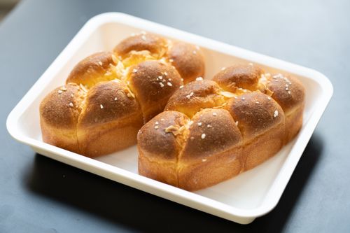 Free Golden brown bread rolls in a white tray, topped with sesame seeds and almonds. Stock Photo