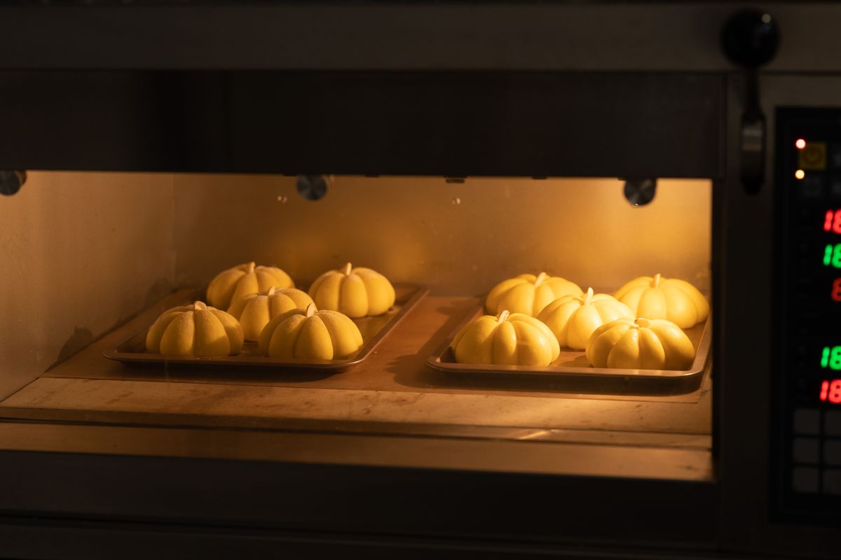 Pumpkin-shaped loaves of bread baking inside a warm, glowing oven