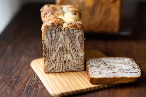 Free Close-up view of a freshly baked marble bread loaf sliced on a wooden board. Stock Photo