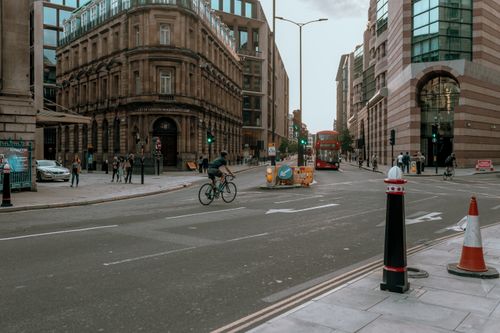Free A busy intersection in London featuring cyclists, pedestrians, and a classic red bus. Stock Photo