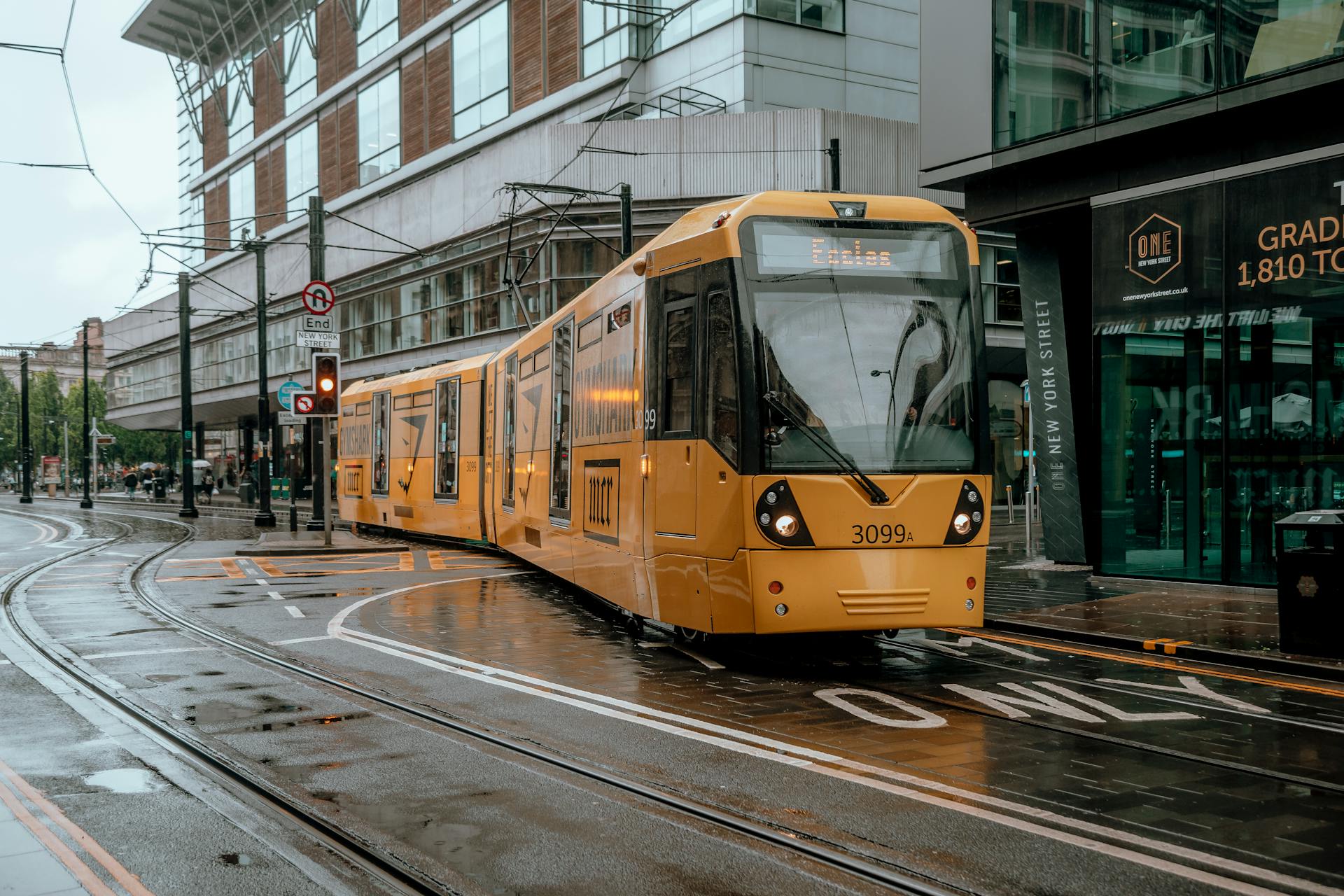 Yellow tram navigating a rainy street in Liverpool city center.