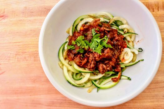 Zucchini noodles topped with rich tomato sauce and fresh herbs, ready to eat.
