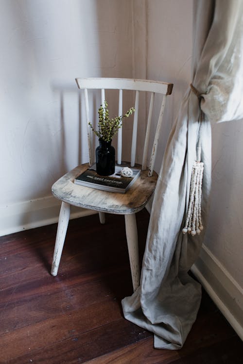 A Vase With Flower and Book on an Old Wooden Chair