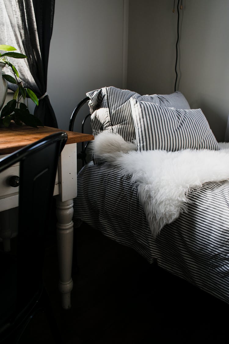 White Furry Textile On  Bed With Black And White Stripe Covers
