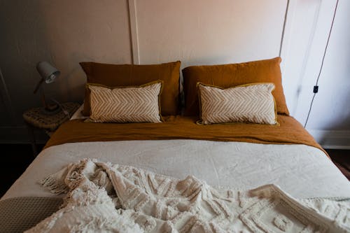 Free Bed with Brown Pillows and Brown and White Linen Stock Photo