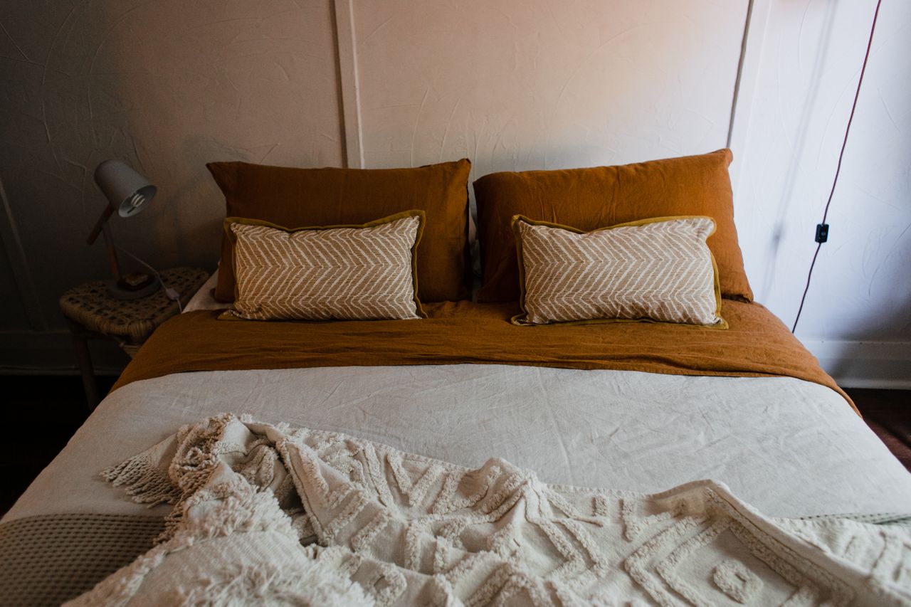 Warm bedroom with rust-colored pillow shams and patterned lumbar pillows on a styled bed