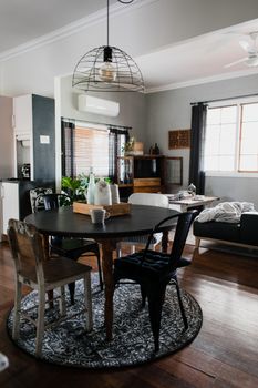 A stylish living room featuring a round table, eclectic chairs, and modern decor.