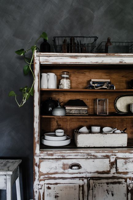 Vintage wooden shelf with plates, jars, and decor creating a rustic farmhouse feel.