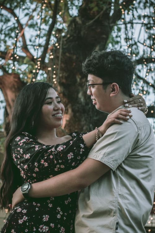 Free A joyful couple embraces under twinkling lights, exuding romance and happiness outdoors. Stock Photo