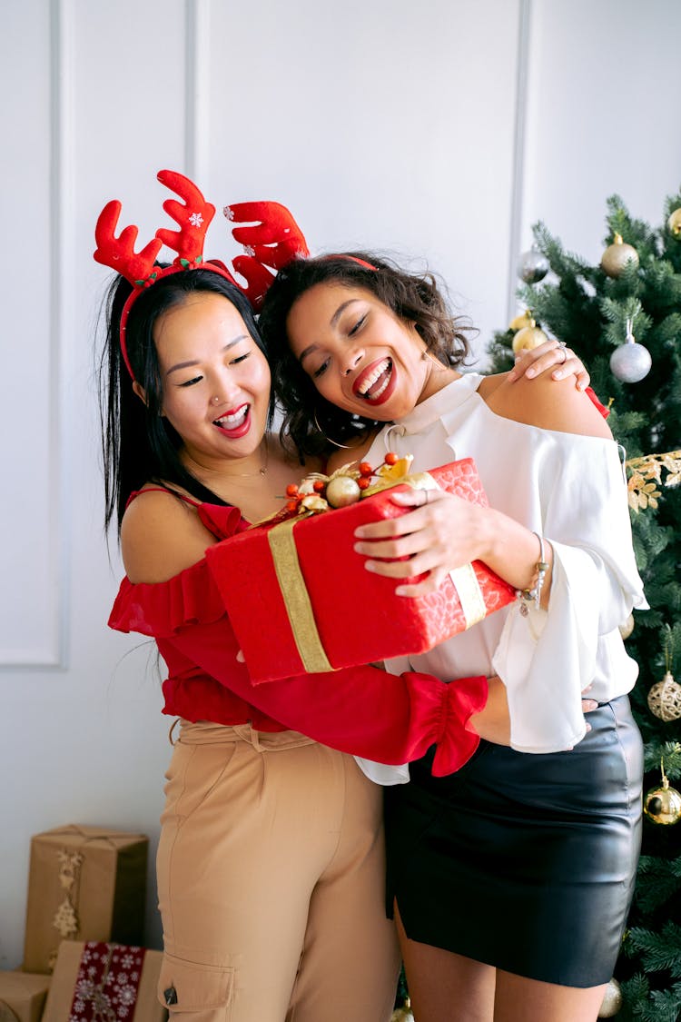 Women Happily Looking At Christmas Present 