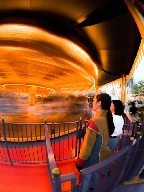 Women standing near fast carousel in amusement park
