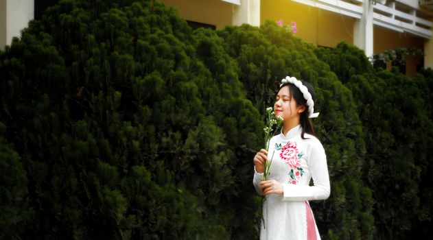 Woman in White Long Sleeve Dress Standing Near Green Plants