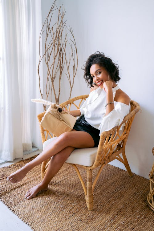 Smiling Woman Sitting on Brown Wooden Armchair With Crossed Legs