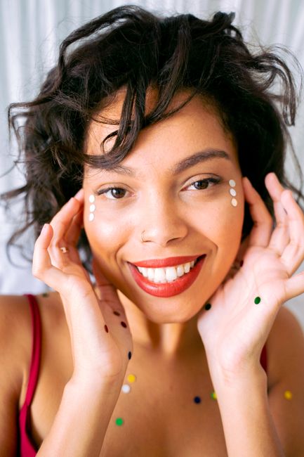 Happy young woman with confetti smiling brightly in a colorful portrait with a playful and vibrant mood.