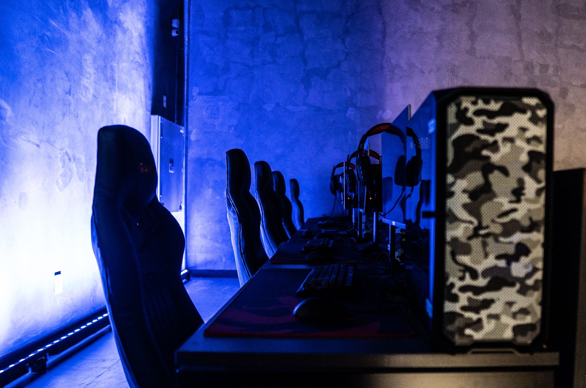 A sleek gaming room setup featuring high-performance computers and ambient blue lighting.