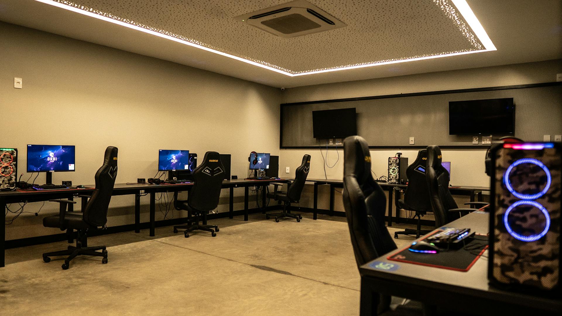 A modern gaming room featuring high-performance PCs, gaming chairs, and sleek design.