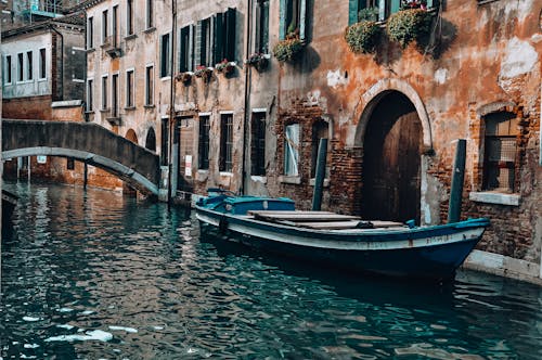 Blue Boat on Canal Beside An Old Building