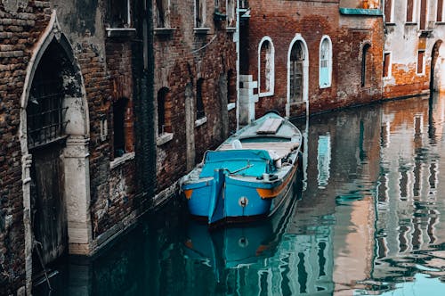 Blue Boat on Canal Near Buildings