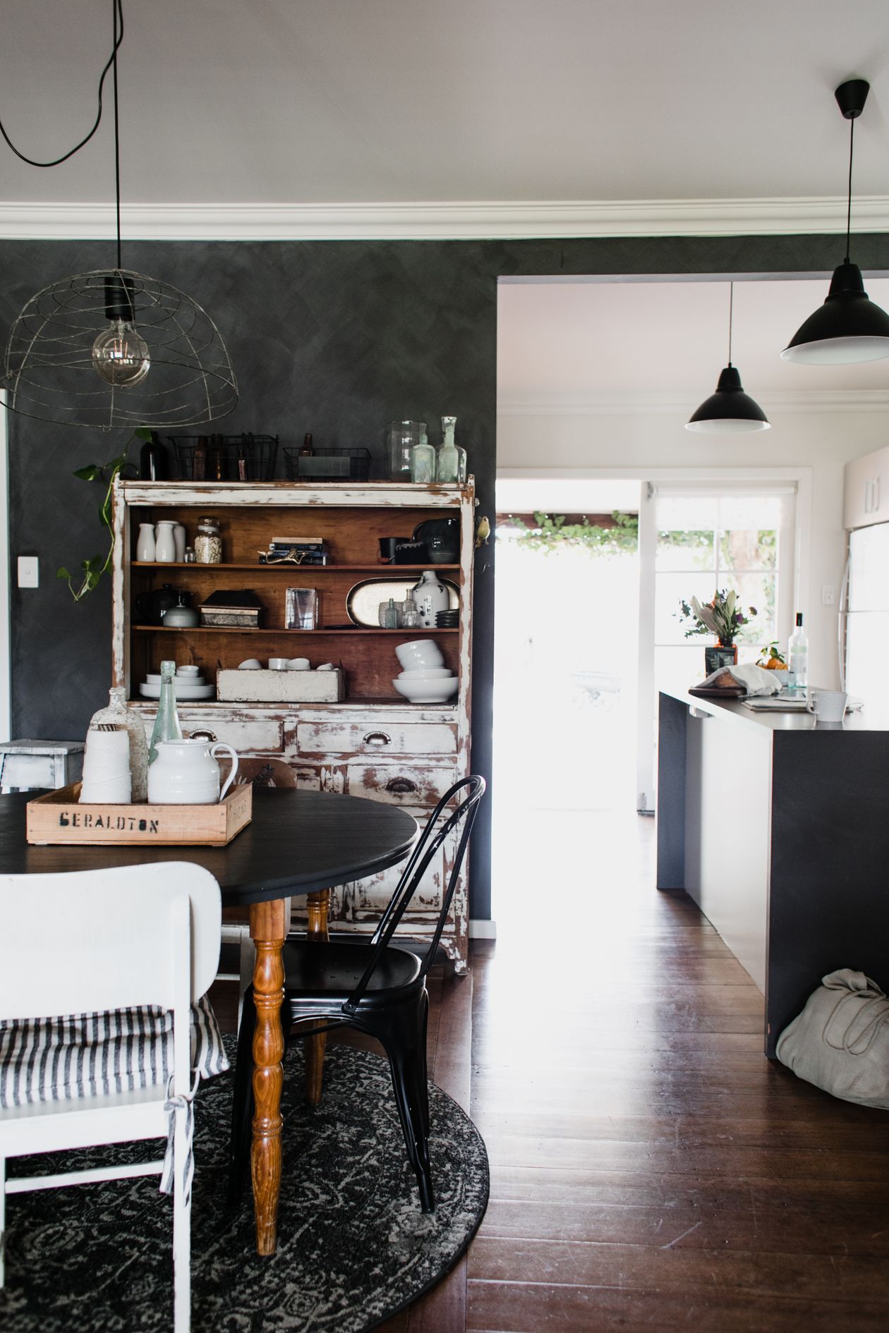 Black round dining table surrounded by mismatched chairs in different styles