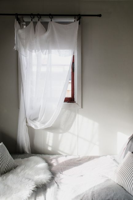 Inviting bedroom with sheer curtains and sunlight on a cozy bed setup.