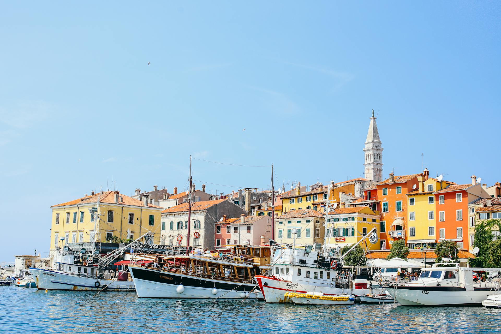 Colorful waterfront buildings with boats in a sunny harbor, ideal for travel imagery.