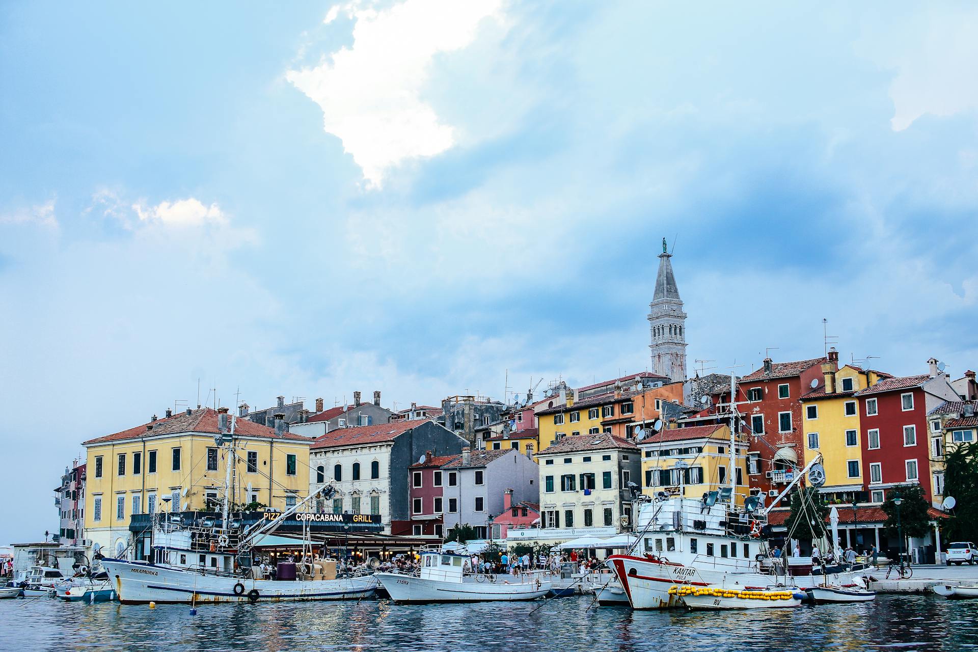 Charming seaside town view with colorful buildings, boats, and historic tower.