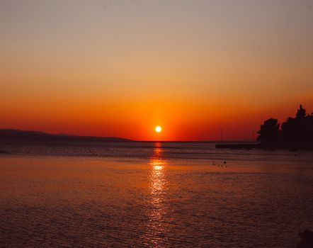 A stunning sunset over the ocean with vivid orange and red hues reflecting off the water.