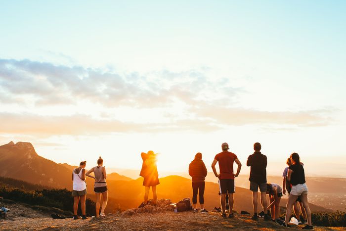 Group of friends watching the sunset together on a mountain trip